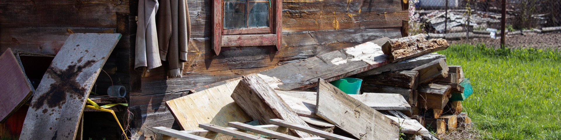 Old wooden rural house with construction waste in the yard.